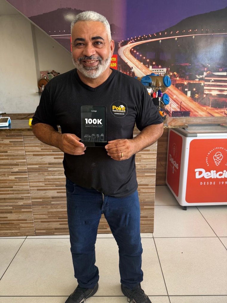 Dono do Point Restaurante segurando o troféu de 100 mil pedidos
